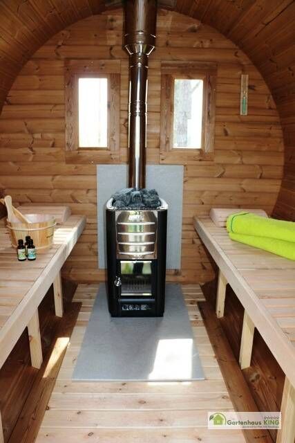 Fass-Sauna Premium Innenansicht mit Holzofen, Wasserkübel und Aufgusskelle, Kopfstützen, Rückwand mit zwei Fenstern