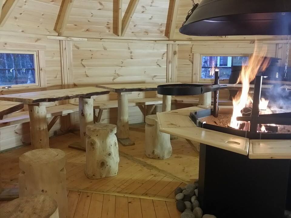 Grillkota Deluxe 25 m² Inneneinrichtung mit Hockern, Tischen, Feuer brennt im Grill