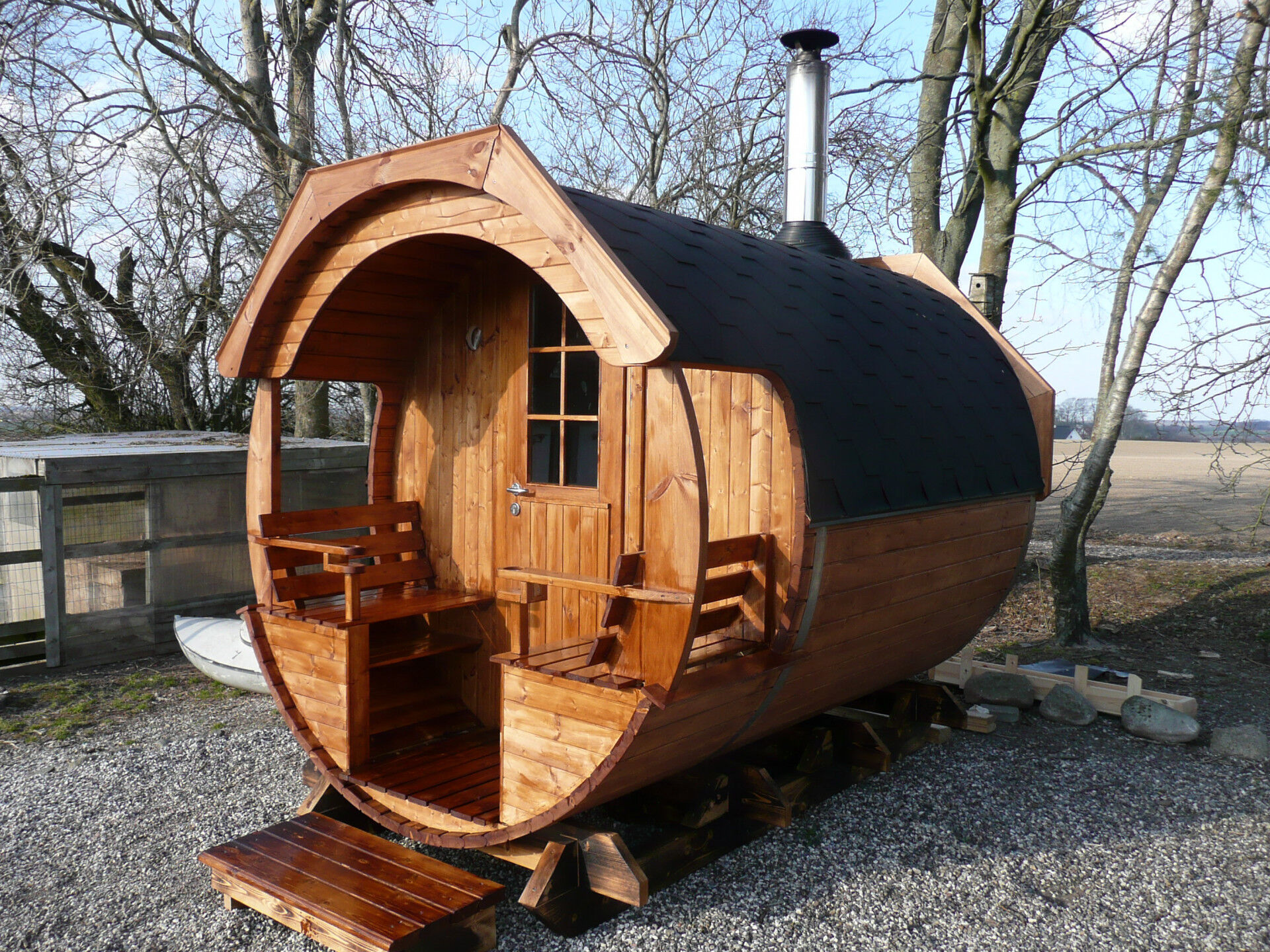 Saunafass Arctic Alex Standard 240x300 aus Thermoholz, Holztür mit Glaseinsatz, Überdachte Terrasse mit zwei Außenbänken