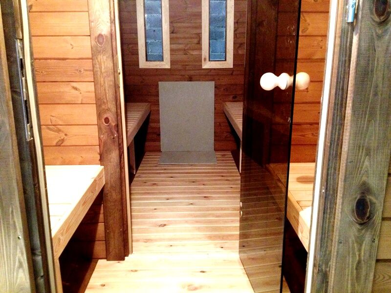 Fass-Sauna Premium Blick durch geöffnete Glastür in Vorraum und Saunaraum mit zwei Fenstern in der Rückwand