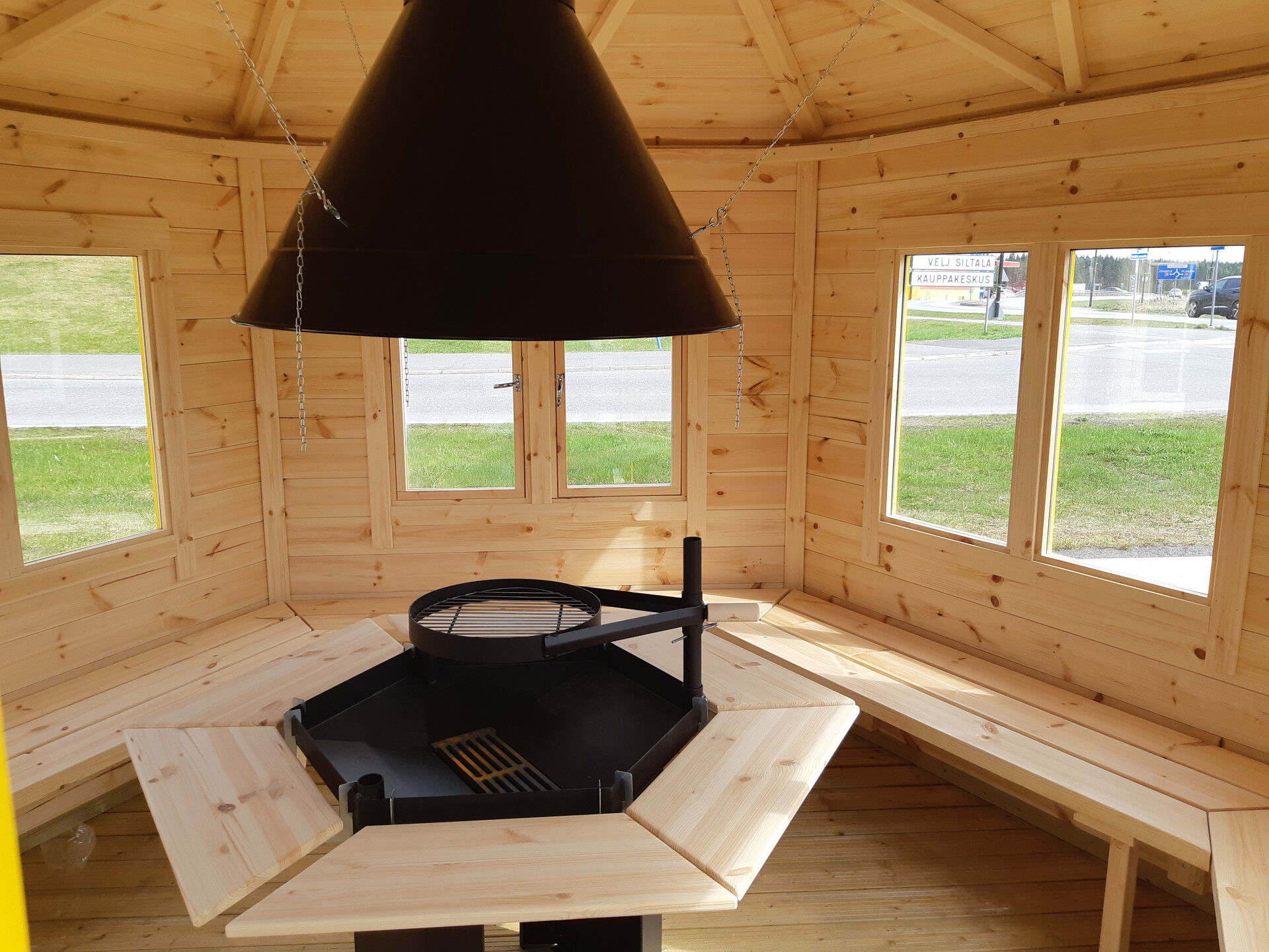 Grillpavillon Victoria 6,5 m² Innenansicht, Schwenkgrill, Rauchabzug, Tische, Bänke und Fenster