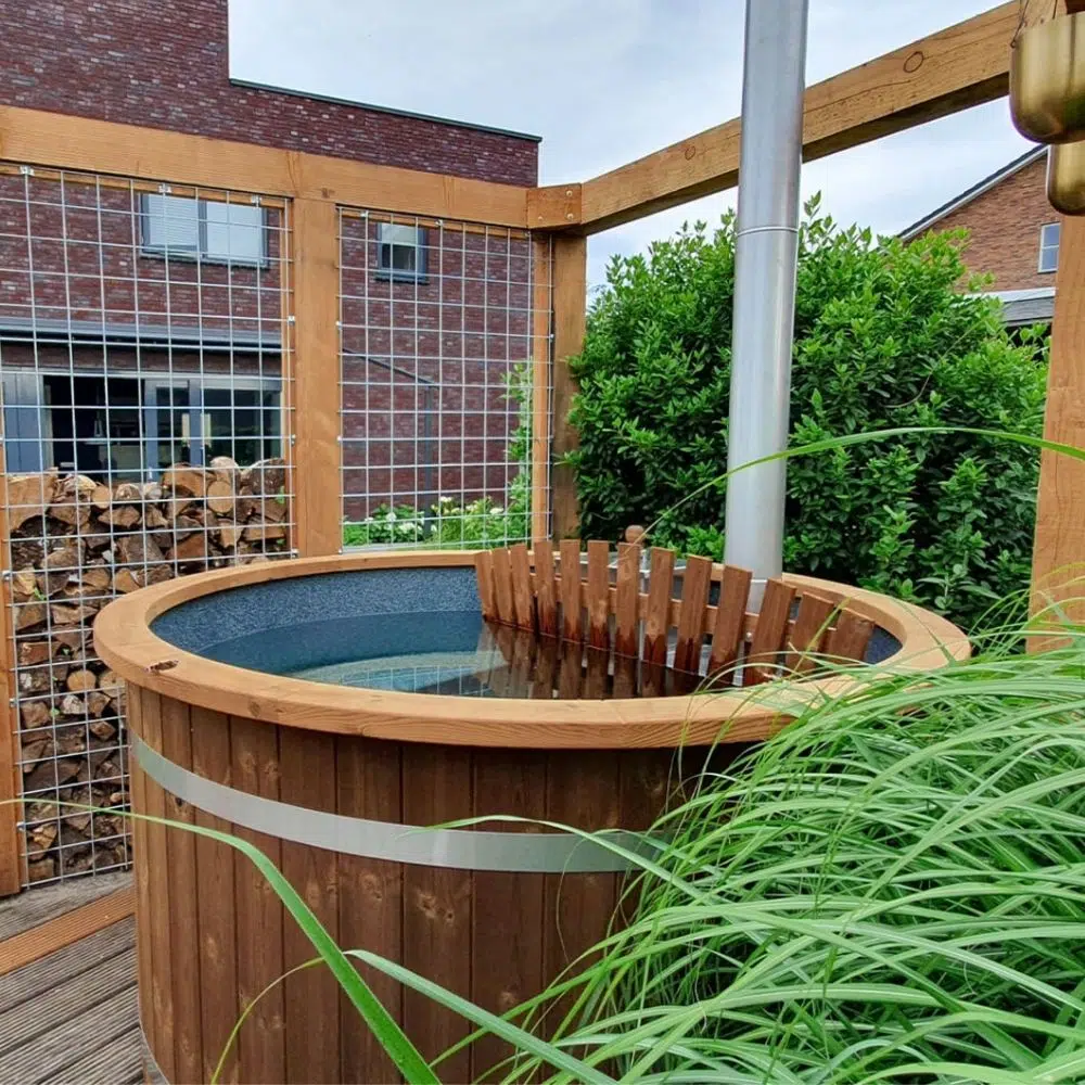 Badebottich Compact mit Verkleidung aus Thermoholz, Holzumrandung und Innenofen auf Terrasse
