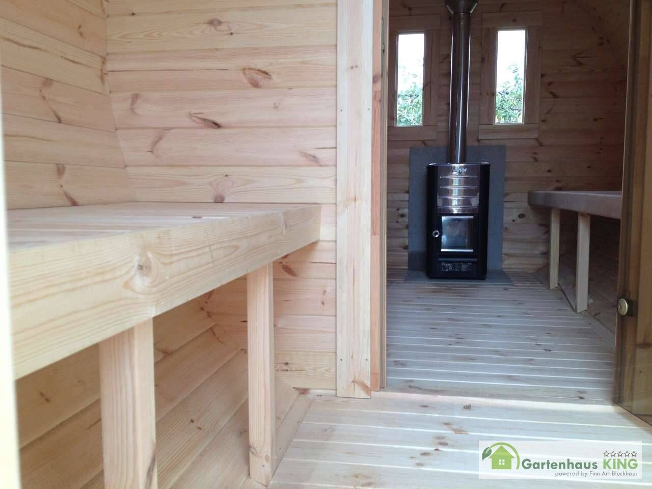 Finn Art Fass-Sauna Premium Blick durch geöffnete Glastür in Innenraum auf Holzofen, zwei Fenster in Rückwand